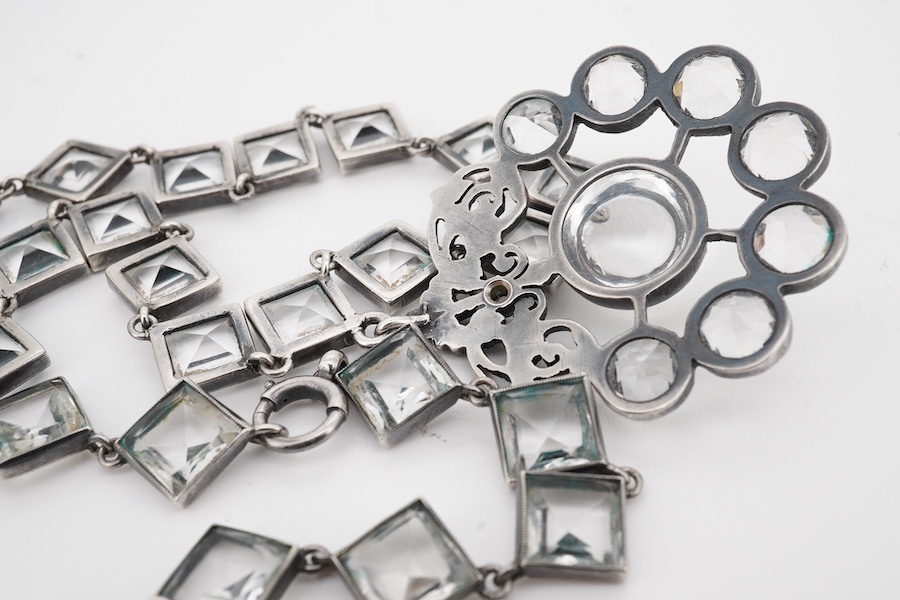 An Arts & Crafts white metal and paste cluster set circular pendant, diameter 33mm, hung from an associated white metal and quartz set necklace, 37cm.